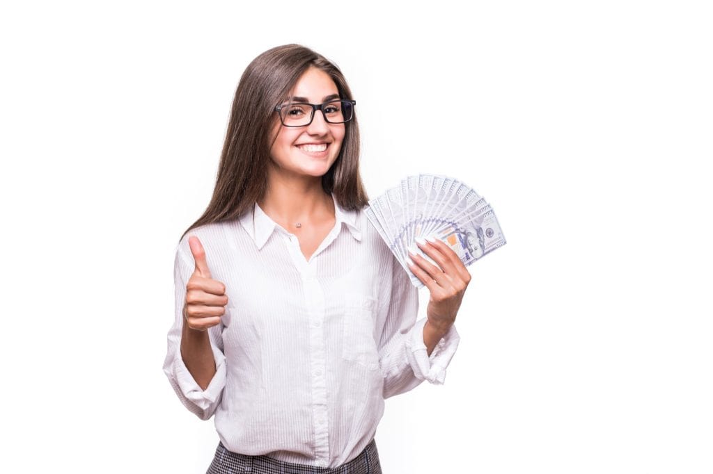 Mulher feliz segurando cédulas de dinheiro e fazendo o sinal de positivo